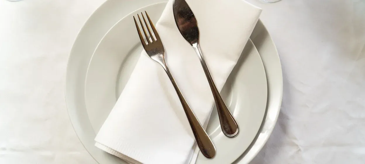 Silverbestick på vit servett och tallrik