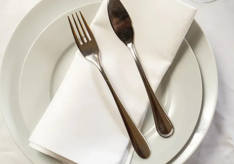 Silverbestick på vit servett och tallrik